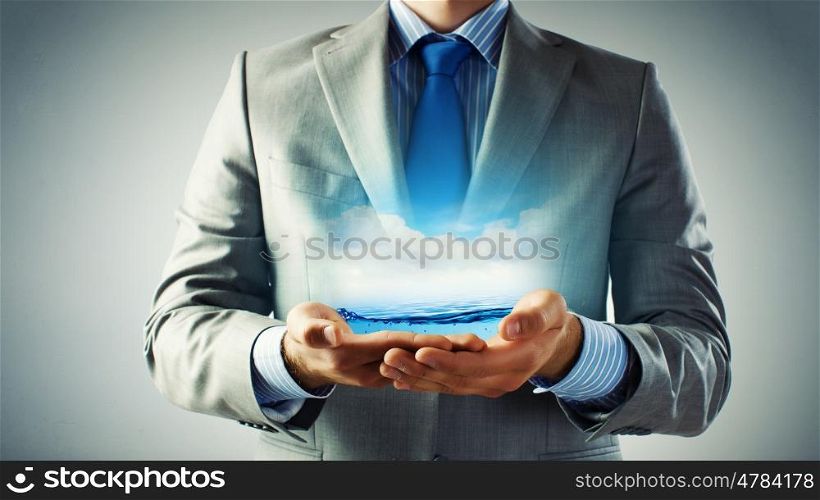 World ocean. Close up of businessman holding clear blue water in palms