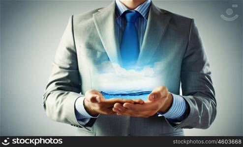 World ocean in hands. Close up of businessman holding clear blue water in palms