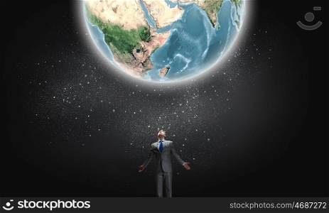 World power. Young businessman and Earth planet above. Elements of this image are furnished by NASA