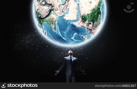 World power. Young businessman and Earth planet above. Elements of this image are furnished by NASA
