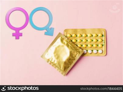 World sexual health or Aids day, condom in wrapper pack and contraceptive pills blister hormonal birth control pills and Male and female gender signs on a pink background, Safe sex concept