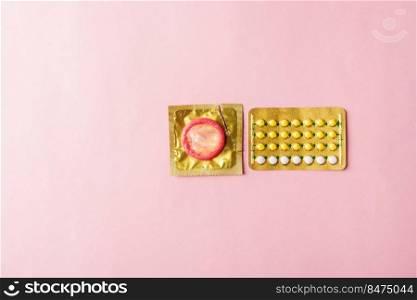 World sexual health or Aids day, condom on wrapper pack and contraceptive pills blister hormonal birth control pills, studio shot isolated on a pink background, Safe sex and reproductive health concept