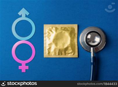 World sexual health or Aids day, flat lay medical equipment, condom in pack, stethoscope and Male, female gender signs, studio shot isolated on dark blue background, Safe sex reproductive health
