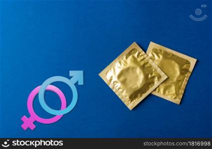 World sexual health or Aids day, Top view flat lay condom in wrapper pack and Male, female gender signs, studio shot isolated on a dark blue background, Safe sex and reproductive health concept