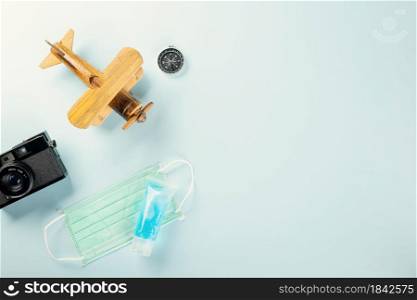 World Tourism Day during coronavirus breakout pandemic, model plane with mask and camera, STOP and safe travel concept, studio shot blue background with copy space, holiday trip vacation concept