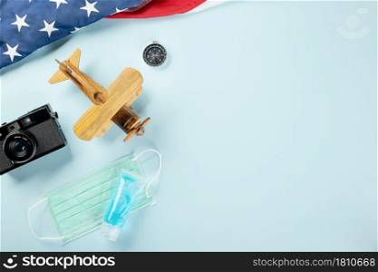 World Tourism Day during coronavirus pandemic, model plane with face mask and American flag, STOP and safe travel, studio shot isolated blue background with copy space, holiday trip vacation concept