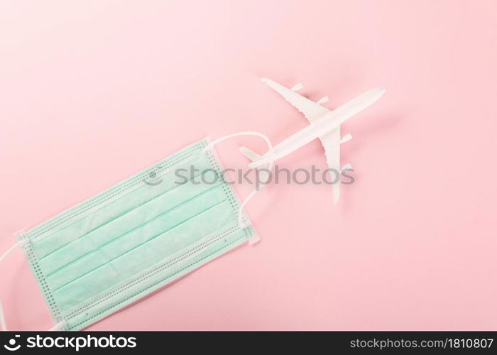 World Tourism Day, Top view model plane and medical face mask, Holiday accessory beach trip travel vacation studio shot isolated pink background with copy space