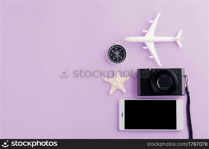 World Tourism Day, Top view of minimal model plane, airplane, starfish, alarm clock, compass and smartphone blank screen, studio shot isolated on purple background, accessory flight holiday concept