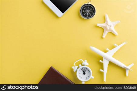 World Tourism Day, Top view of minimal model plane, airplane, starfish, alarm clock, compass and smartphone blank screen, studio shot isolated on yellow background, accessory flight holiday concept