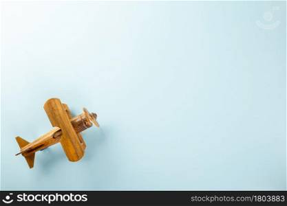 World Tourism Day, toy of passenger plane on rustic wood, Wooden airplane model top view, studio shot isolated blue background with copy space for text, holiday trip travel vacation concept