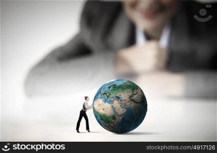 Worldwide business. Businesswoman looking at miniature of woman rolling Earth planet. Elements of this image are furnished by NASA