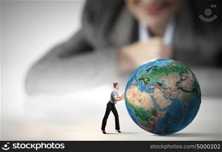 Worldwide business. Businesswoman looking at miniature of woman rolling Earth planet. Elements of this image are furnished by NASA
