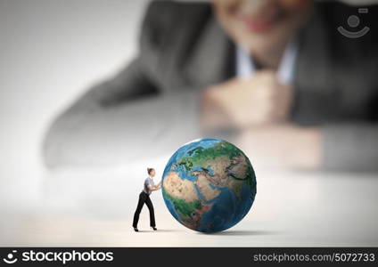 Worldwide business. Businesswoman looking at miniature of woman rolling Earth planet. Elements of this image are furnished by NASA