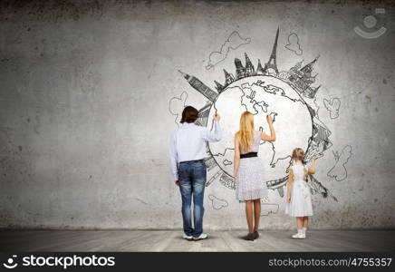 Worldwide traveling. Rear view of family drawing Earth planet on wall