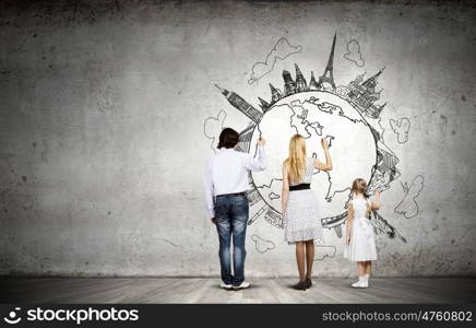 Worldwide traveling. Rear view of family drawing Earth planet on wall