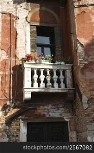 Worn building with balcony and flowers in Venice, Italy.