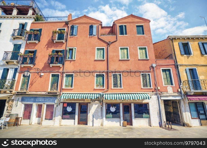 Worn building withj a small shop with decorative awnings on a summer day in Italy