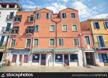Worn building withj a small shop with decorative awnings on a summer day in Italy