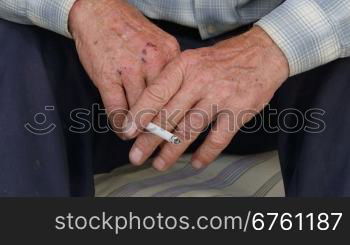 Worn wrinkled hands of senior man with cigarette