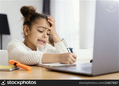 worried little girl home during online school with laptop
