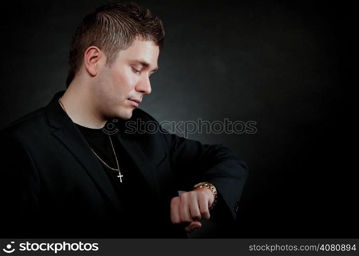 Worried man looking at watch wind clock (wristwatch) black background