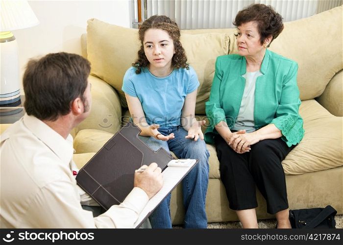 Worried mother looks on as her daughter talks to a therapist.