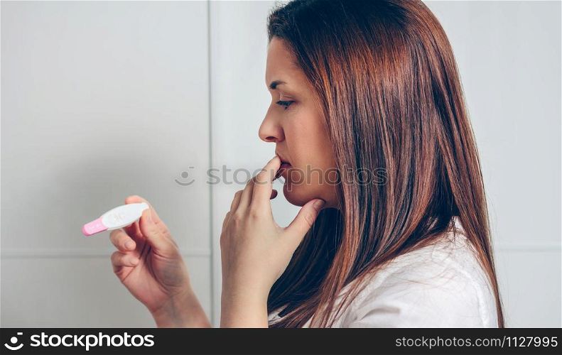 Worried pregnant woman looking at a pregnancy test