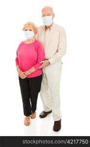 Worried senior couple wearing face masks to protect against flu epidemic. Isolated on white.