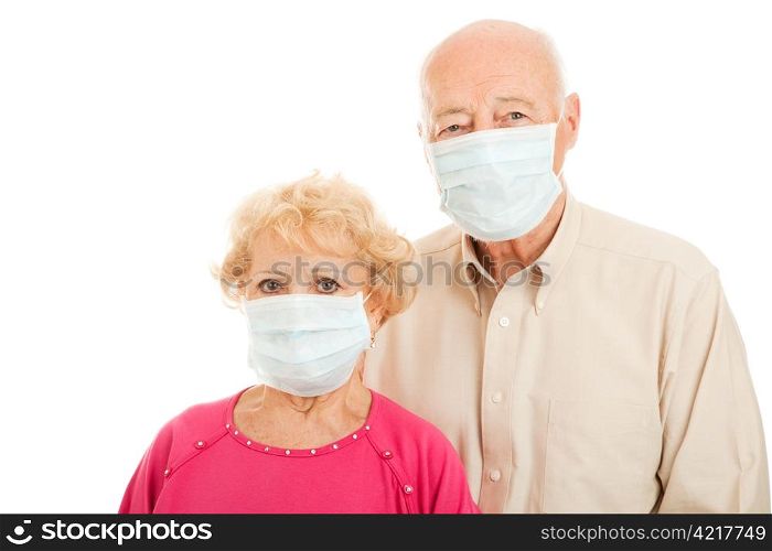 Worried senior couple wearing surgical masks to protect against an epidemic. Isolated.