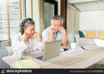 Worried Senior man and woman having problem about Debts. Stressed Asian Elderly Couple calculate their monthly expense in the house. Saving, Financial and economic crisis