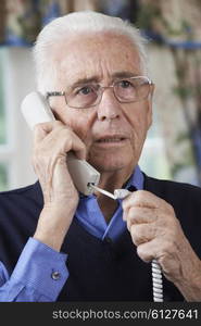 Worried Senior Man Answering Telephone At Home