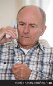 Worried Senior Man Answering Telephone At Home