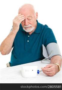 Worried senior man monitors his blood pressure at home.