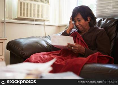 Worried Senior Woman Sitting On Sofa Looking At Bills