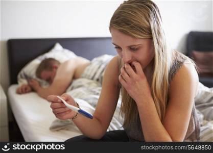 Worried Teenage Girl In Bedroom With Pregnancy Testing Kit