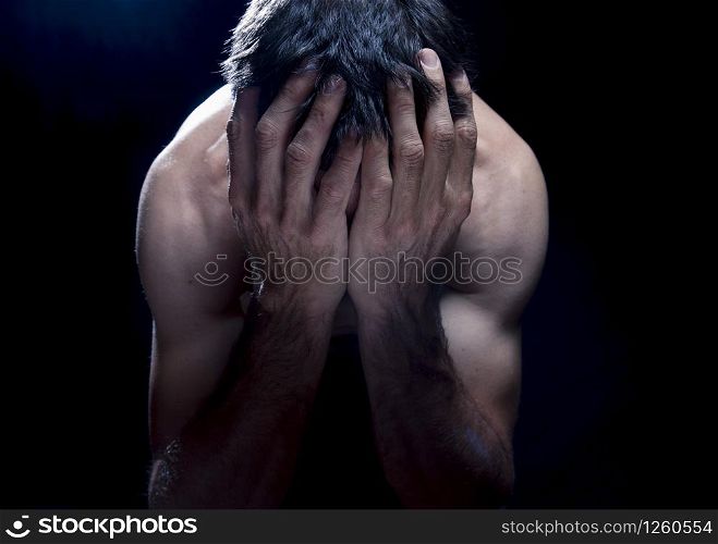 worried white man with hands in head in trouble in a dark room or black background.concept of sadness