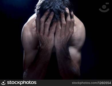 worried white man with hands in head in trouble in a dark room or black background.concept of sadness