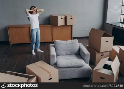 Worried woman holding her head standing near boxes with packed things feels sad due to relocation. Upset girl homeowner or tenant moving out dwelling. Owner eviction, financial problem, foreclosure.. Upset woman homeowner gets stressed by relocation. Owner eviction, financial problem, foreclosure