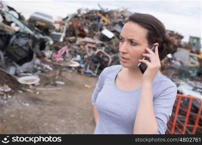 worried woman on the phone at a junk-yard