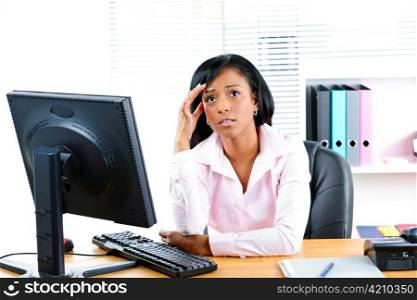 Worried young black business woman at desk in office