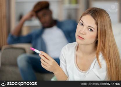 worried young woman looks at pregnancy test
