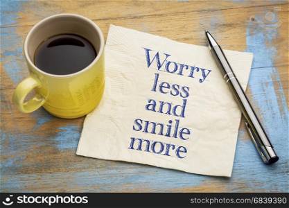 Worry less and smile more - handwriting on a napkin with a cup of espresso coffee