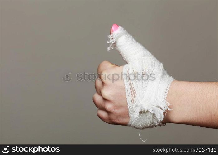 wounded female hand tied elastic bandage, human injury finger on gray background