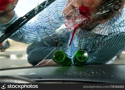 Wounded pedestrian with his head on the smashed windscreen of a car, with two empty beer bottles on the dashboard - the effects of drinking and driving