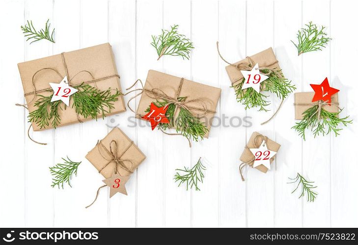 Wrapped gifts Advent calendar with christmas tree branches decoration on bright wooden background. Flat lay