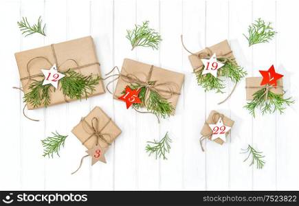 Wrapped gifts Advent calendar with christmas tree branches decoration on bright wooden background. Flat lay