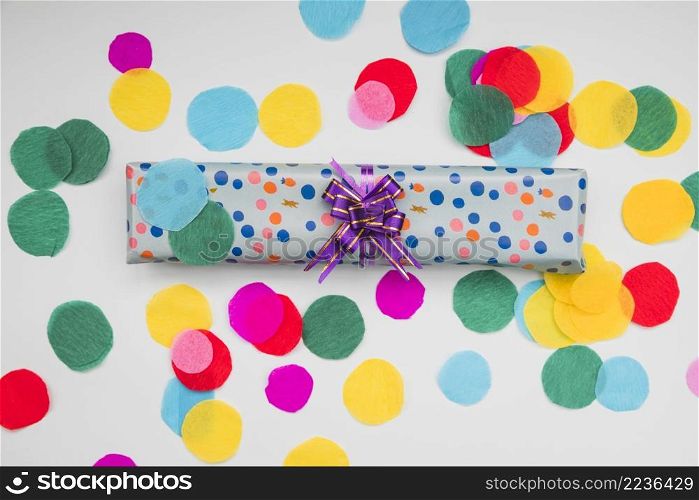 wrapped polka dot gift box with circular cut out colored paper white background