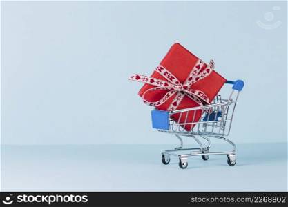 wrapped red gift box shopping cart blue background