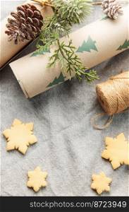 Wrapping paper with a pine branch and Christmas cookies on a textile background. The concept of preparing for the Christmas holiday. Flat lay. Copy space.  
