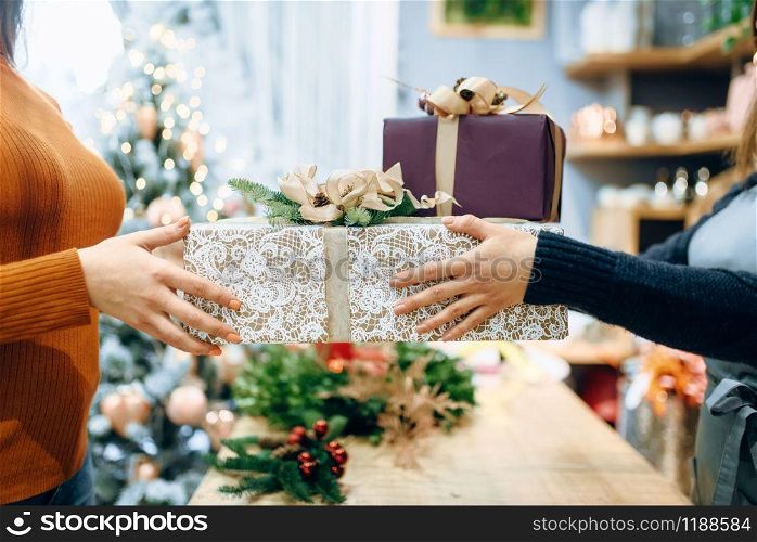 Wrapping service seller gives to customer christmas gift box. Buyer ordered a package of present, festive packing. Wrapping service seller gives to customer gift box